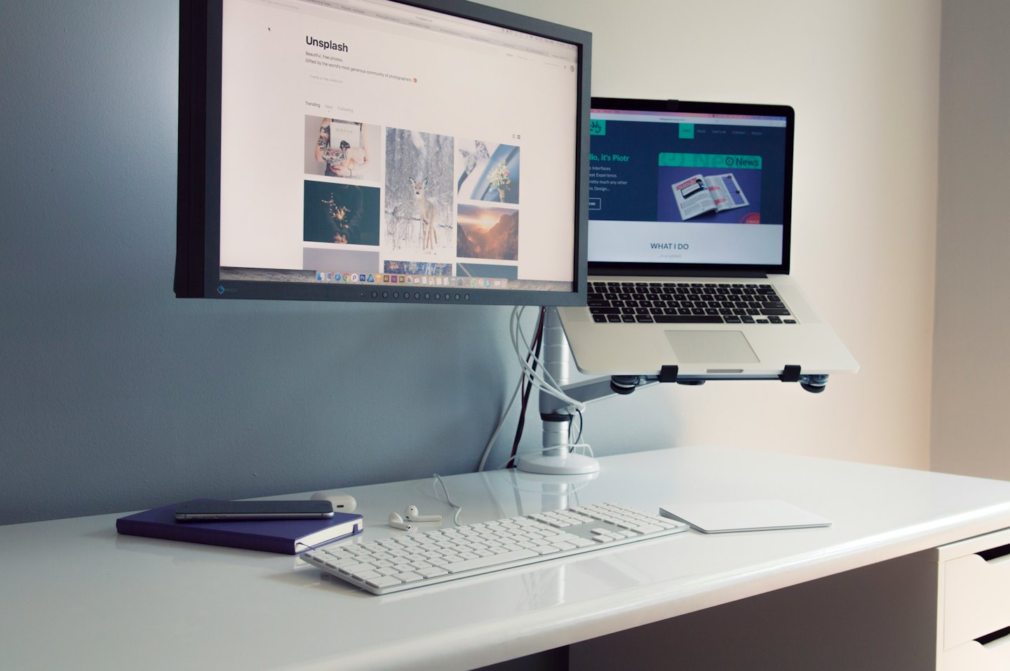 Een opgeruimd bureau met dubbele beeldschermen en een laptopstandaard.