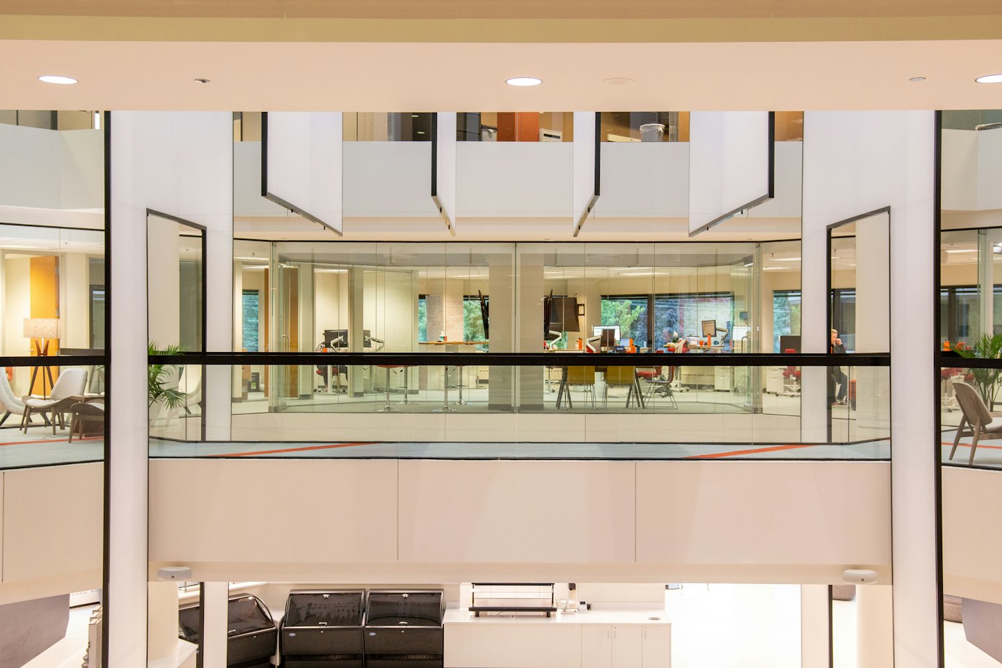 Moderne kantoor-atrium met glazen ruimtes en eigentijds meubilair.