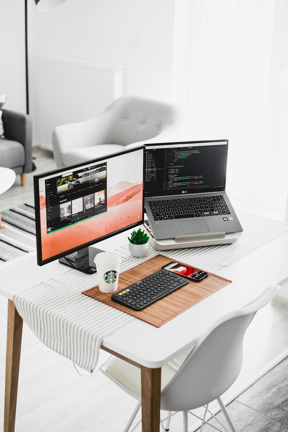 Moderne thuiskantoor met laptop, externe monitor met code en bureau-accessoires.