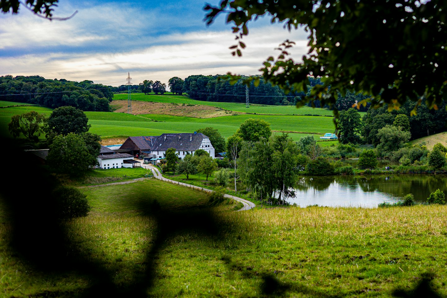 Witte gebouwen van het woonhuis liggen te midden van weelderige groene velden bij een meer.
