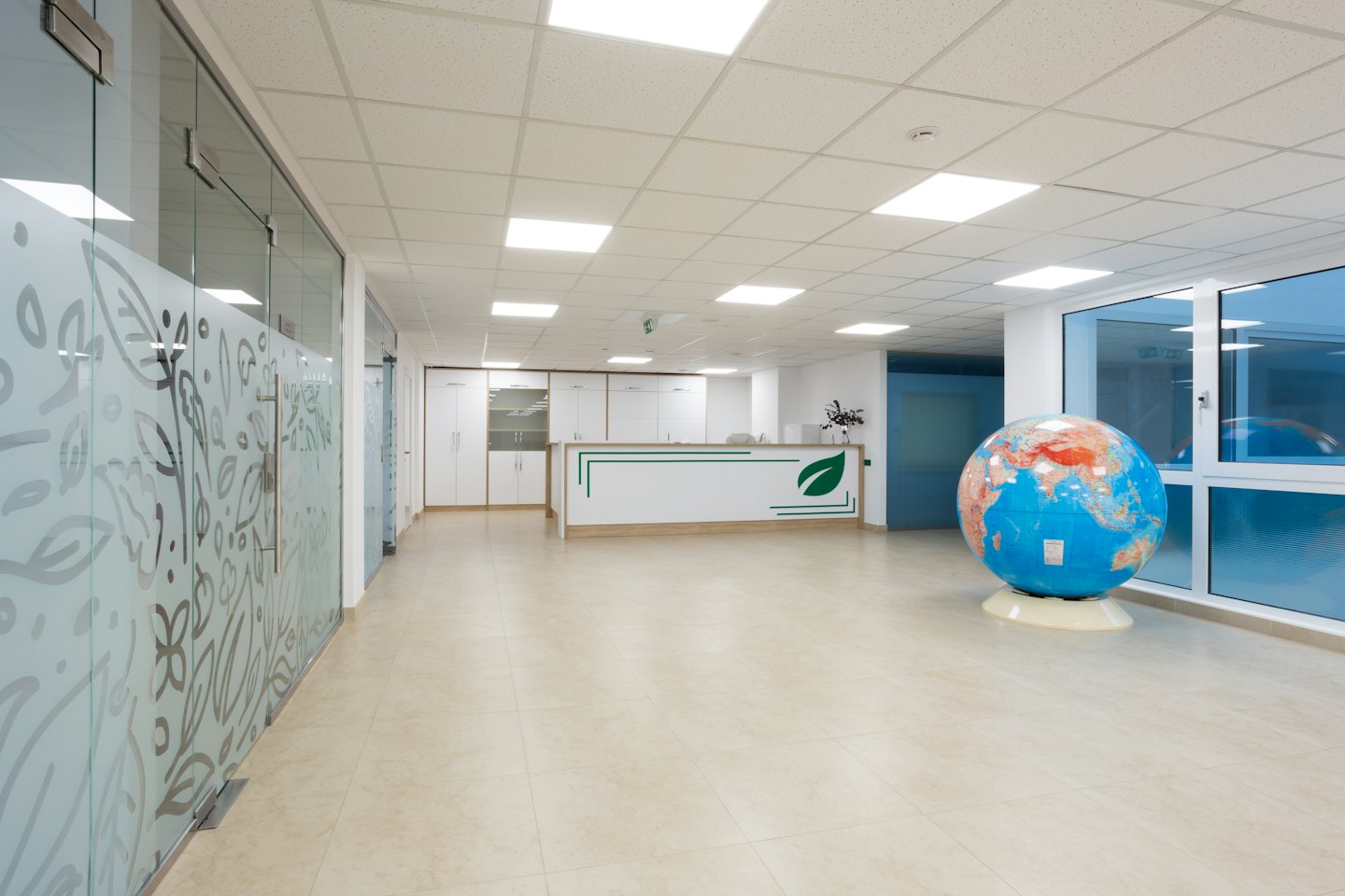 Moderne receptiebalie in een kantoor met een wereldbol en matglazen scheidingswanden.