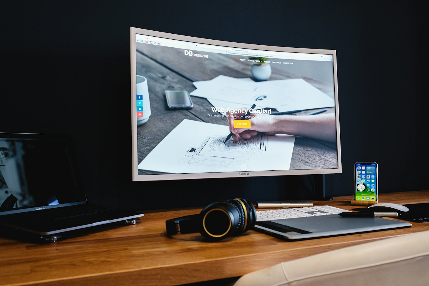 Bureau van een ontwerper met gebogen monitor, laptop en tekentablet.